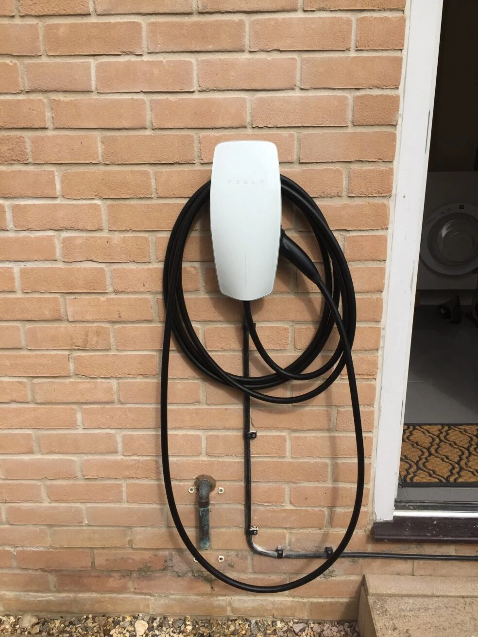 Tesla wall charging station mounted on a brick wall