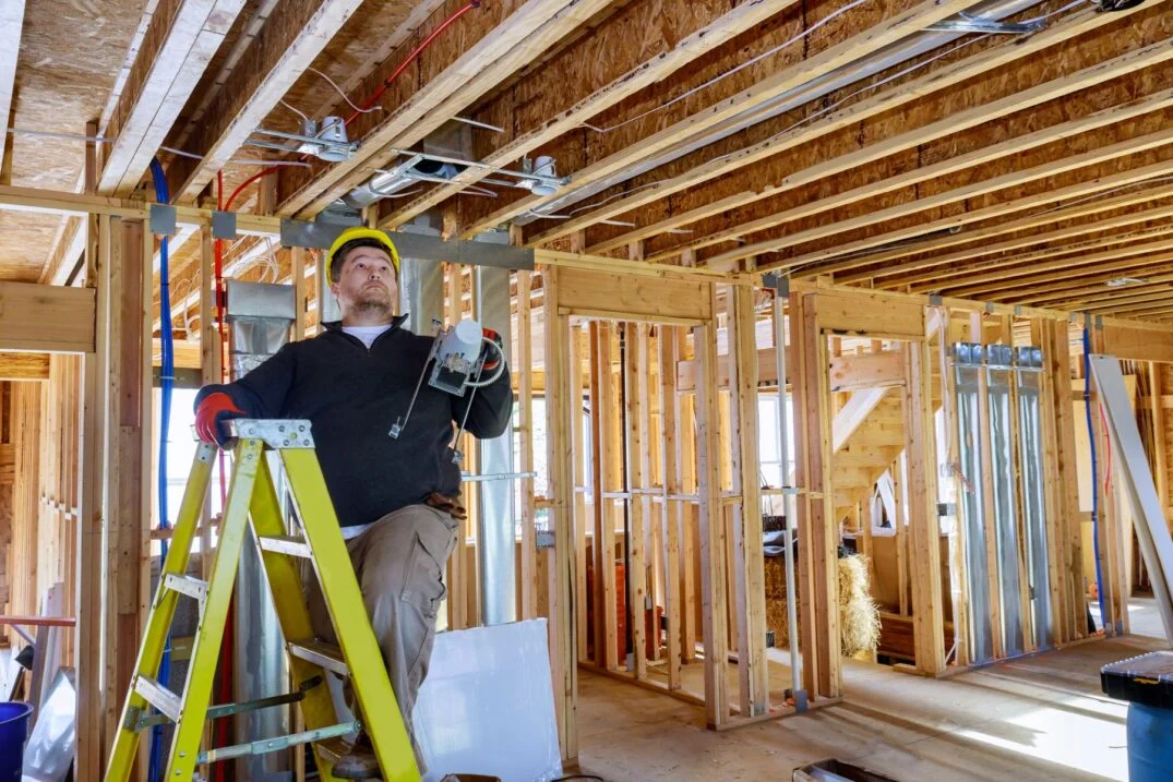 Construction worker using tools on a ladder