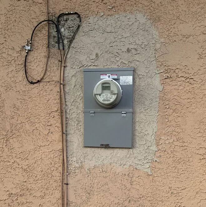 Electric meter mounted on a textured wall